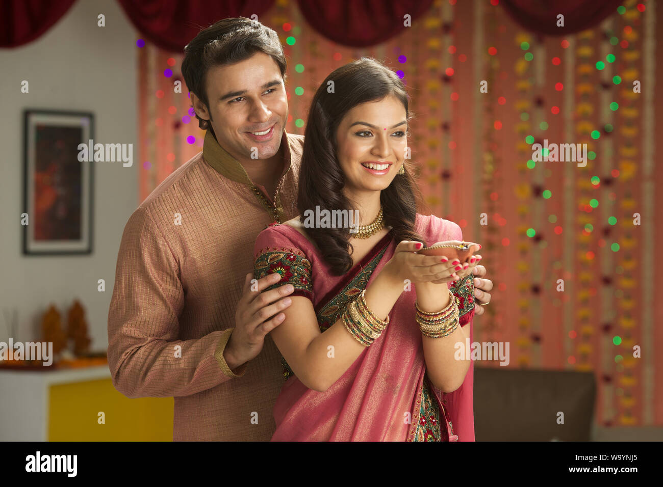 Young couple holding a Diya and smiling Stock Photo