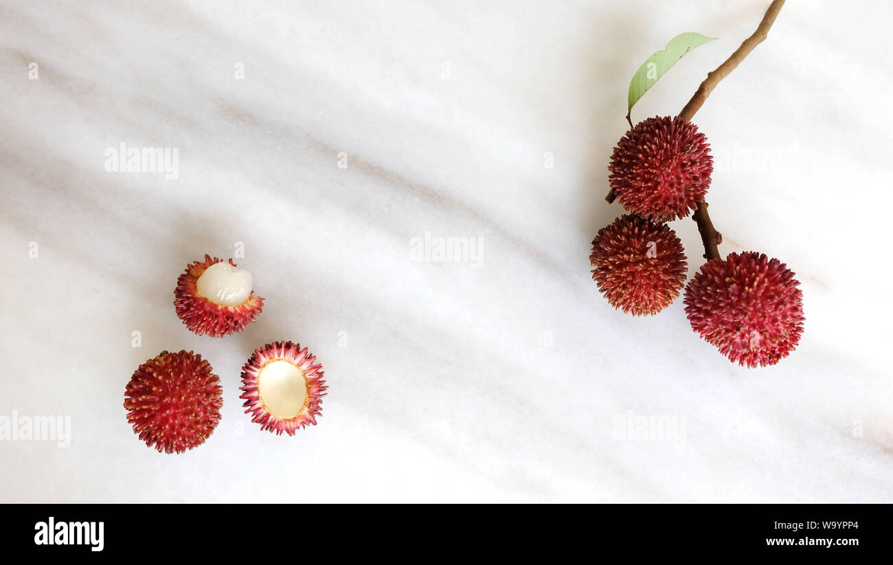 Pulasan fruits on marble bakcground. Scientific name Nephelium ramboutan-akea, pulasan is a red tropical fruit that is closely allied to rambutan. Stock Photo