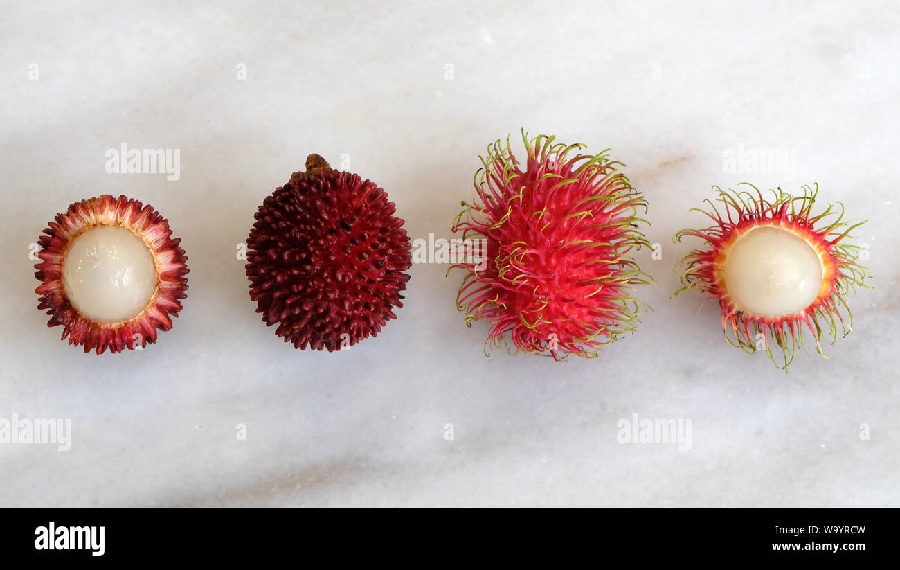 Top view of pulasan and rambutan fruit, arranged side by side. Both are tropical fruits from southeast Asia, and sometimes confused for one another. Stock Photo