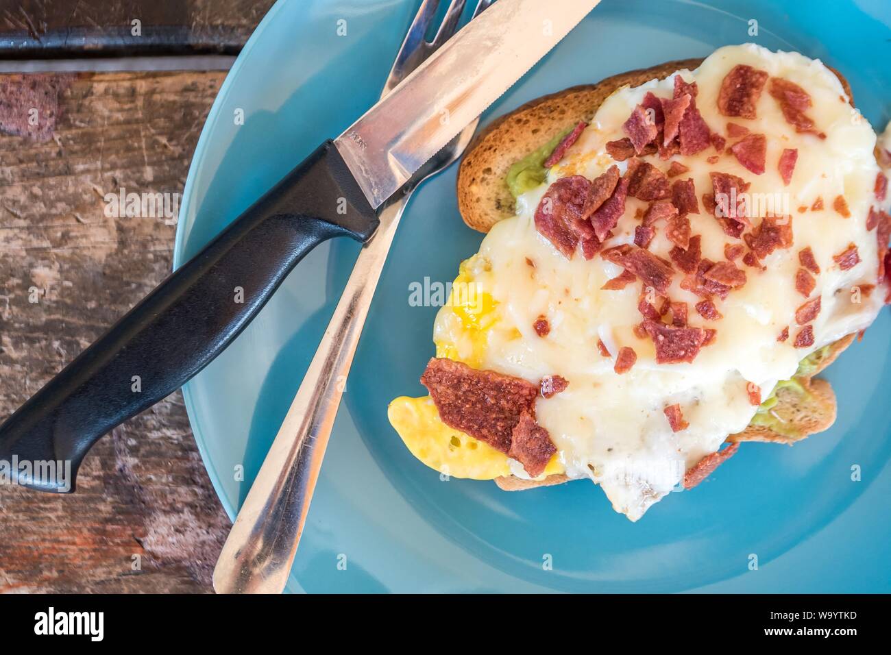 A closeup shot of a tasty egg sandwich with cut sausage on a blue plate Stock Photo
