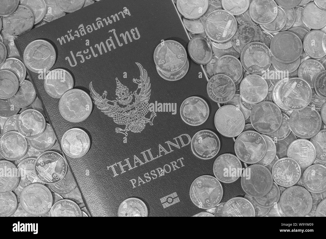Black and white thai passport on a pile of coins thai. Stock Photo