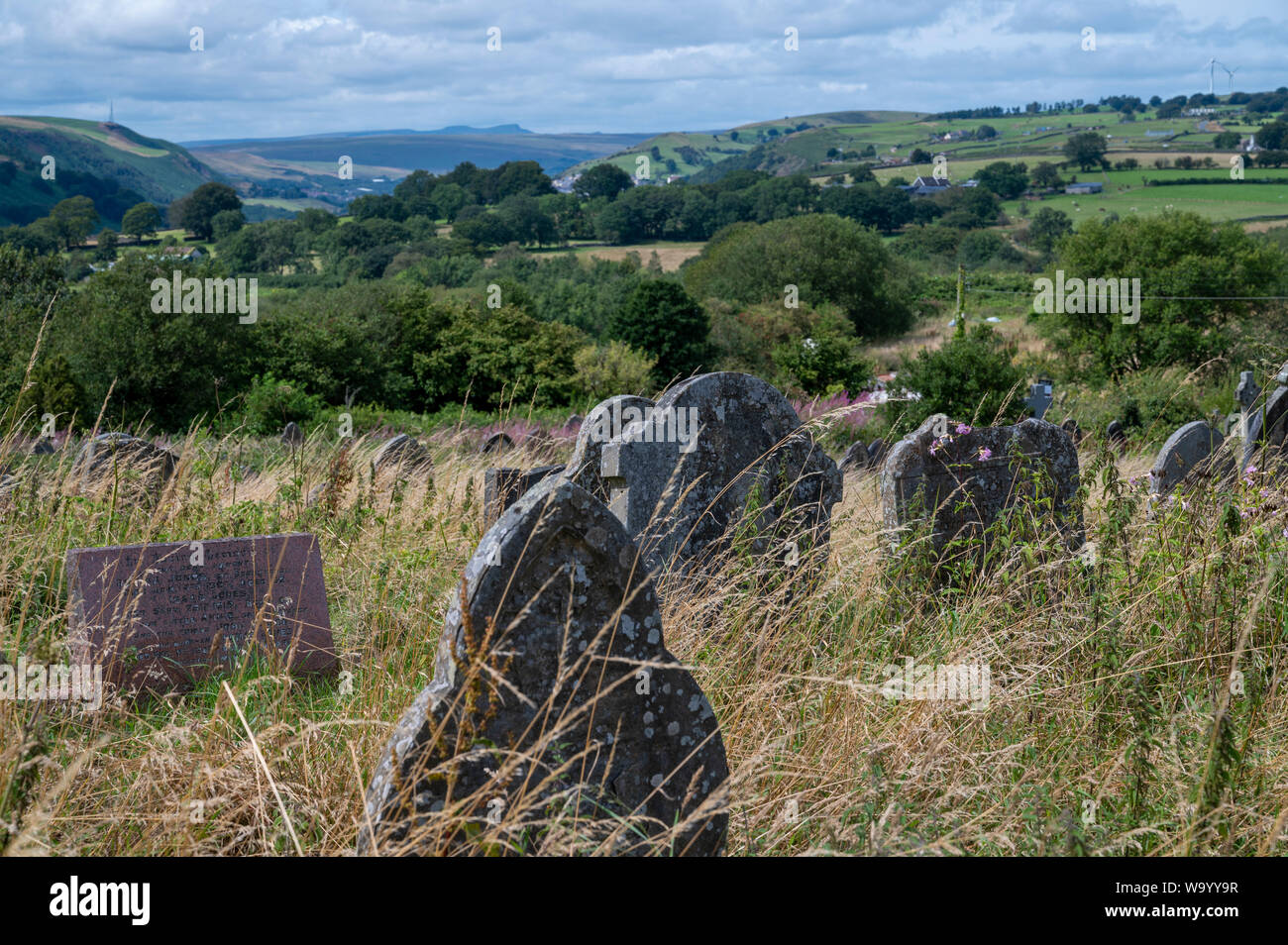 A view from the overgrown graveyard at St Sannan’s Church, Bedwellty, South Wales, UK looking north to The Brecon Beacons mountains of Penyfan and Cor Stock Photo