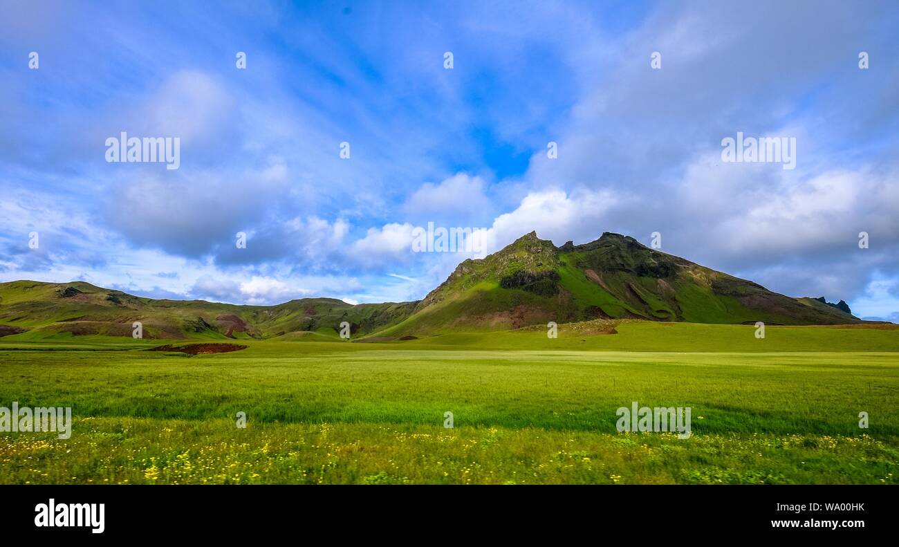 Grassy field with mountains in the distance under a cloudy sky Stock ...