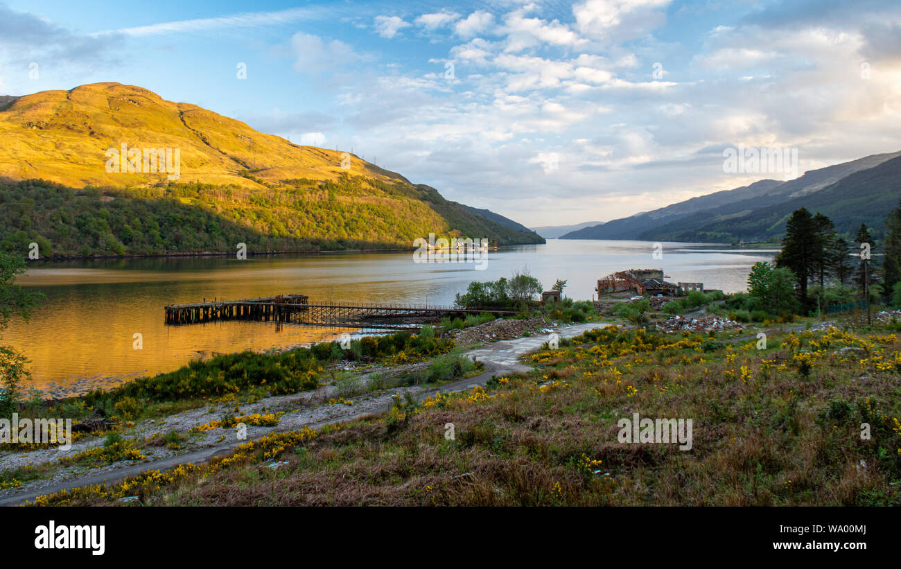 The derelict remains of the World War II era Torpedo Testing Station stand on the shores of Loch Long amongst the Arrochar Alps mountains of the Highl Stock Photo