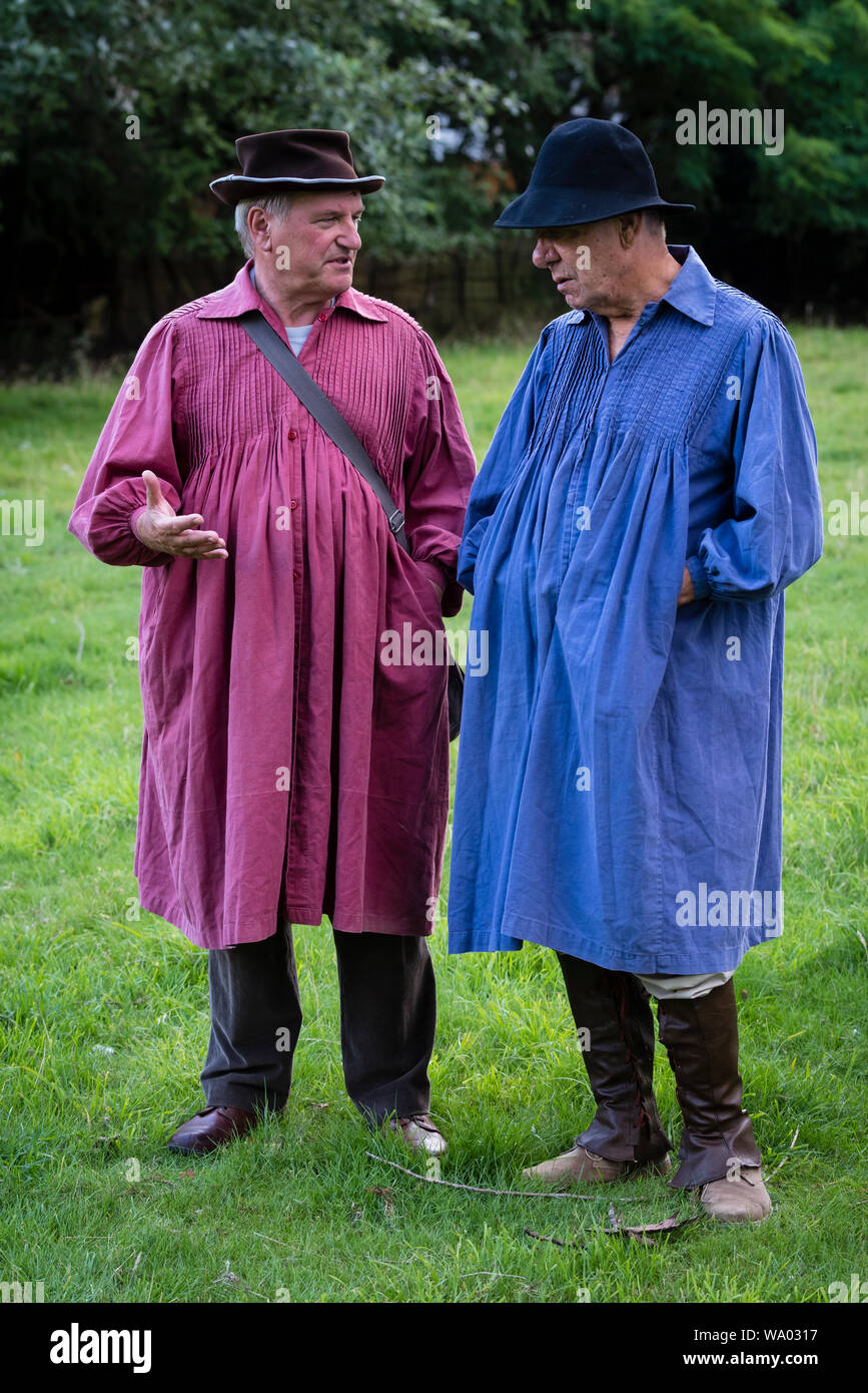 Two men dressed in coloured smocks as 19c farmworkers for a BBC