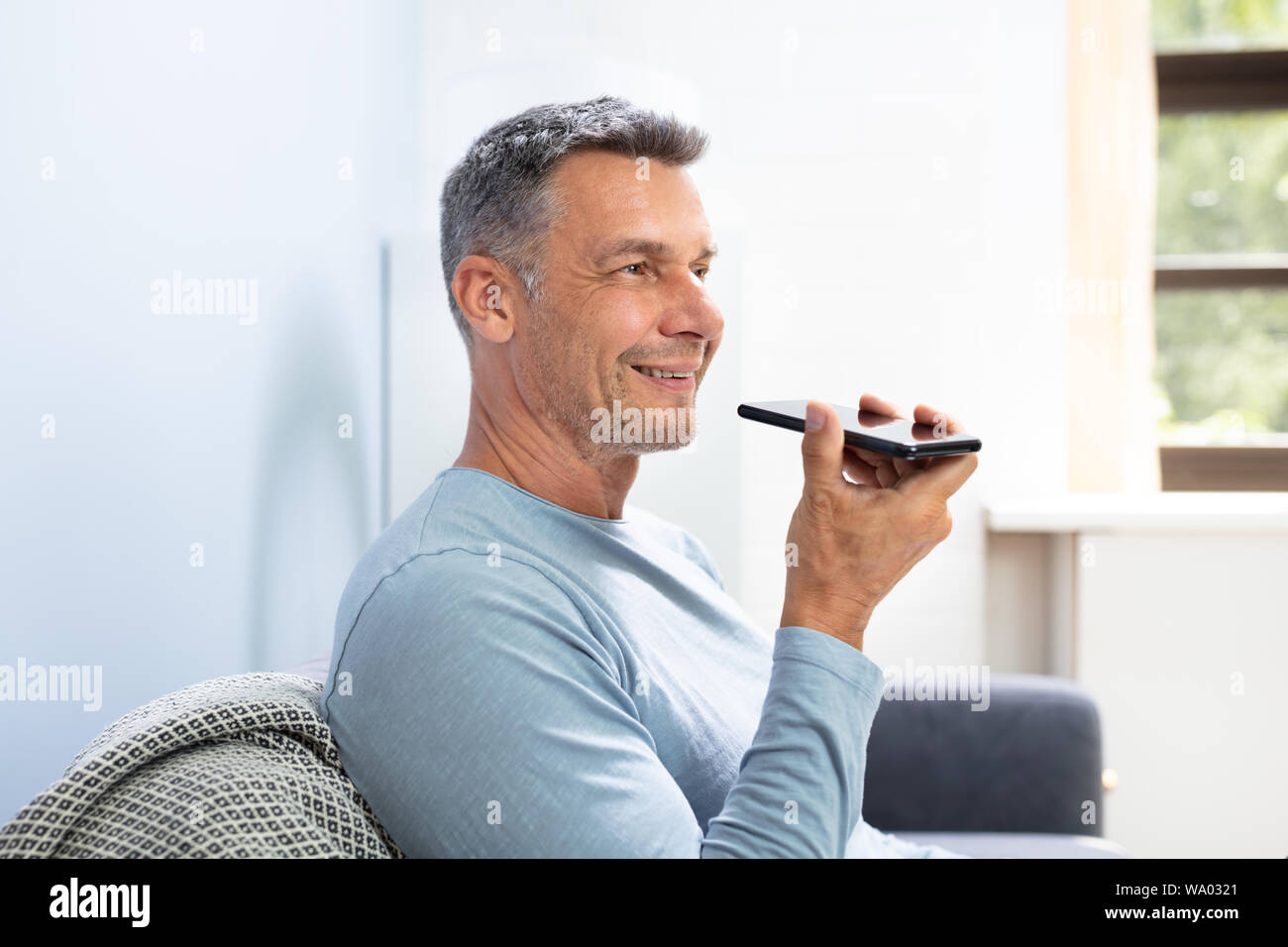 Close-up Of A Beard Man Using Voice Recognition Function On Mobile Phone Against White Background Stock Photo