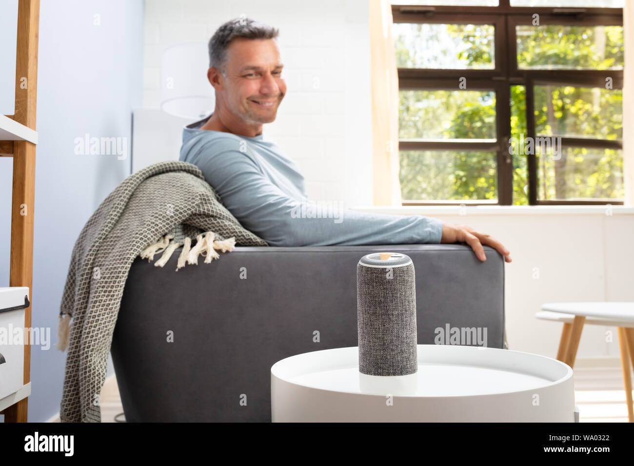 Close Up Of Wireless Speaker In Front Of Man Sitting On Sofa Stock