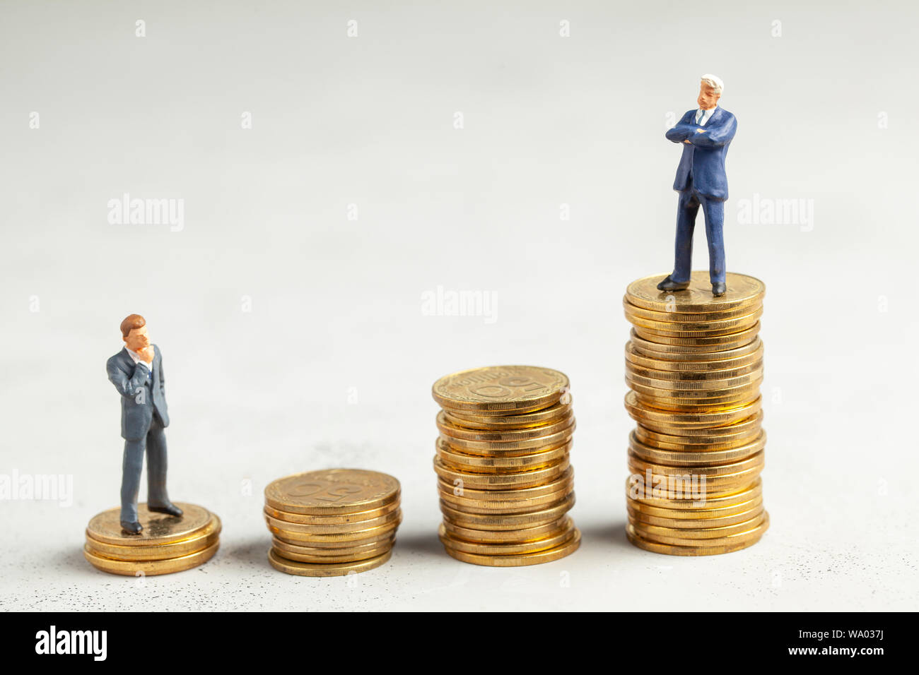 Successful businessman with big profits at the top of the stairs by coins and less successful businessmen with small companies. Adequate investment in the company Stock Photo