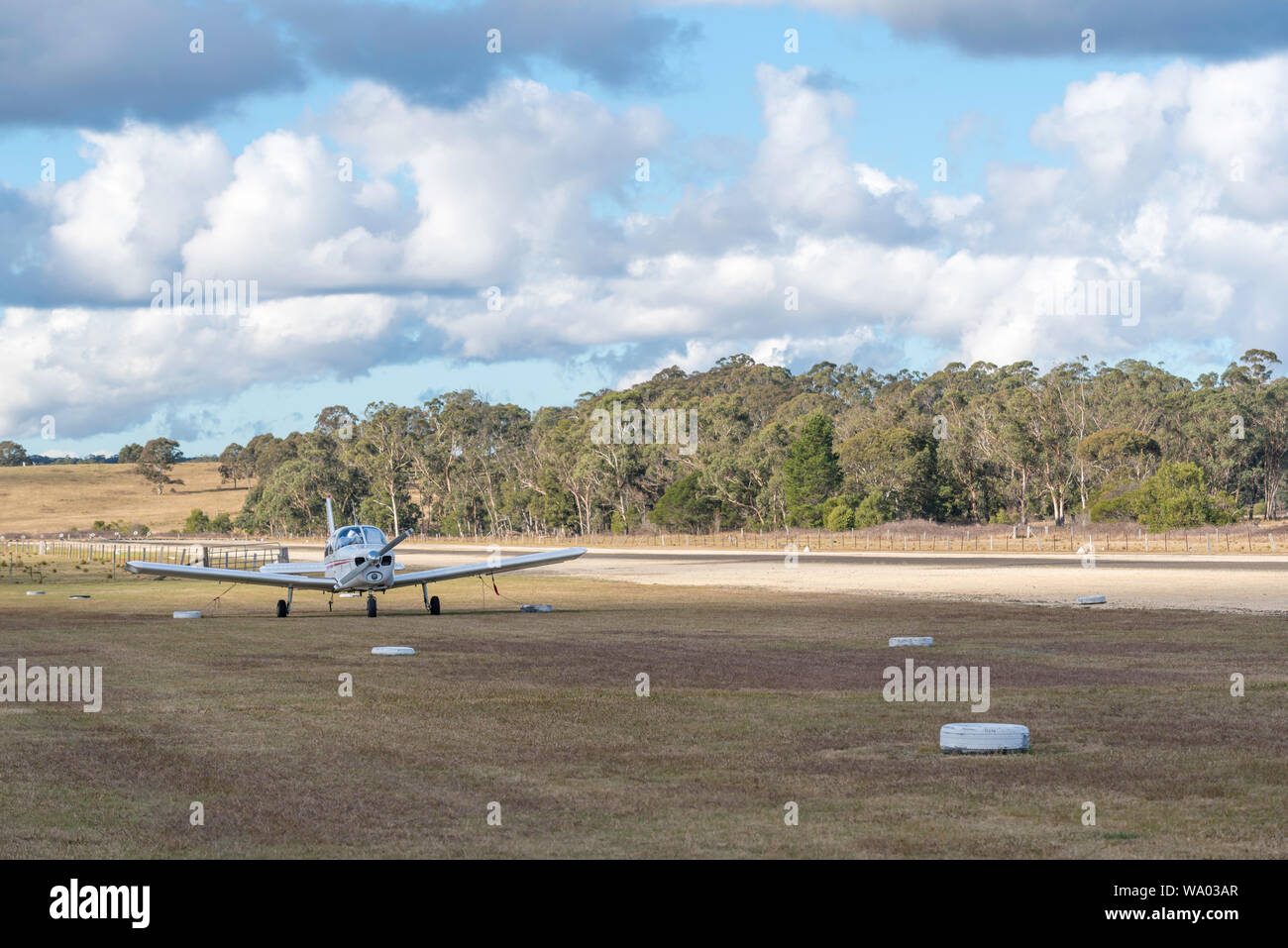 A single light plane sits parked beside the runway at the small regional airstrip at Mittagong Aerodrome in the Southern Highlands of New South Wales Stock Photo