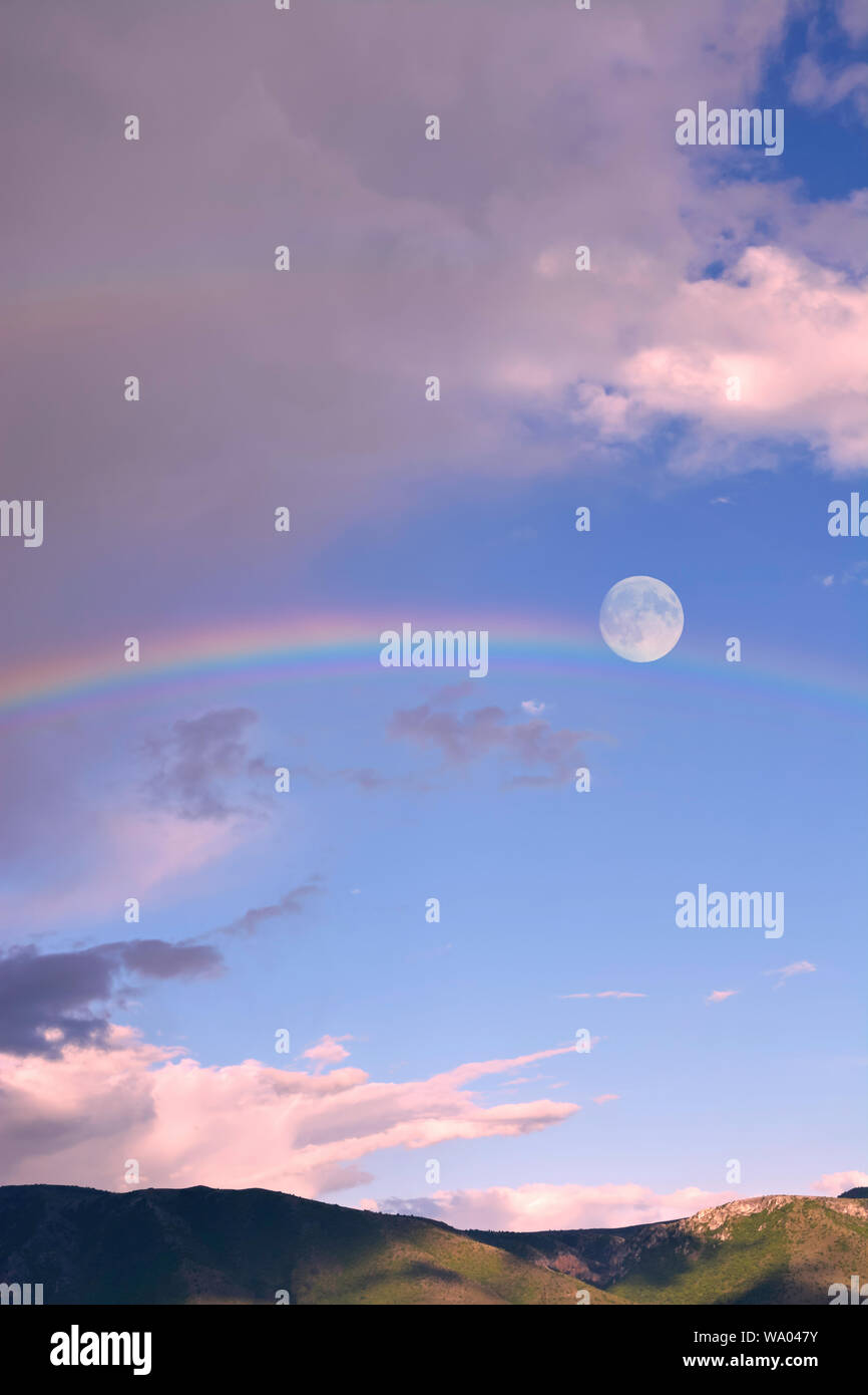 Skyscape with full moon and rainbow Stock Photo