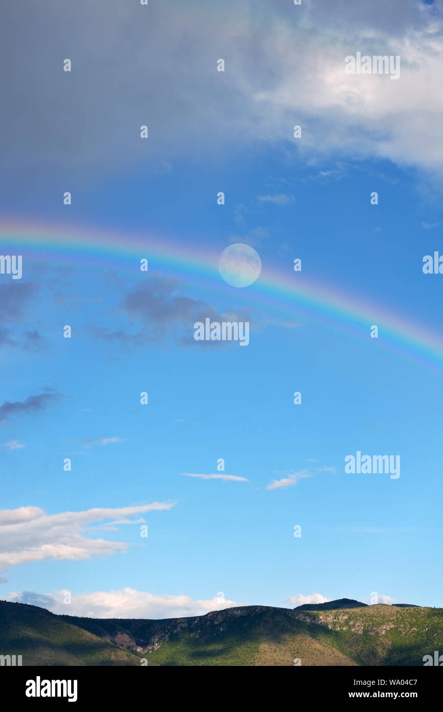 Scenery in the mountain after rain with a rainbow and full moon Stock Photo