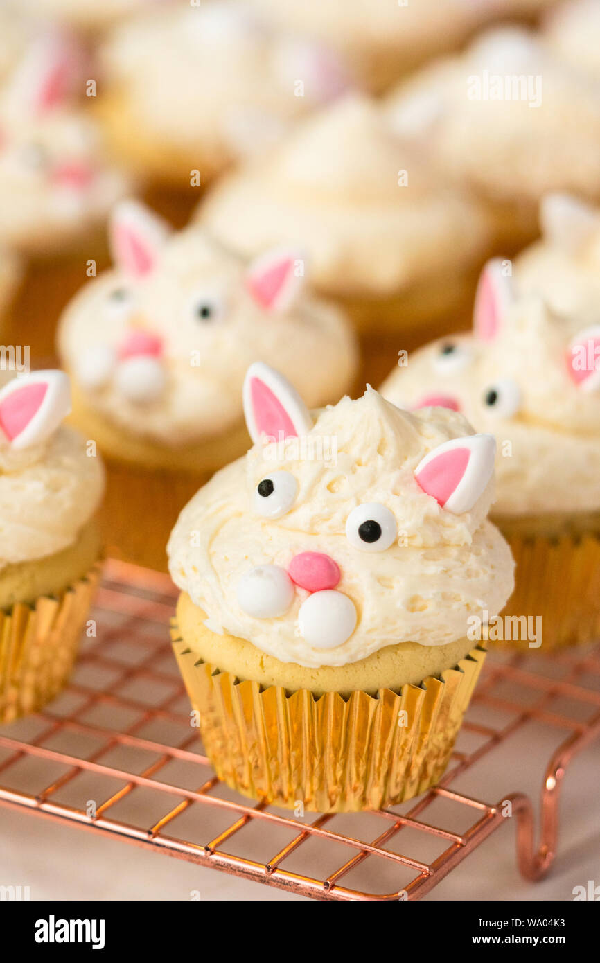 Decorating vanilla cupcakes with a white buttercream icing and bunny