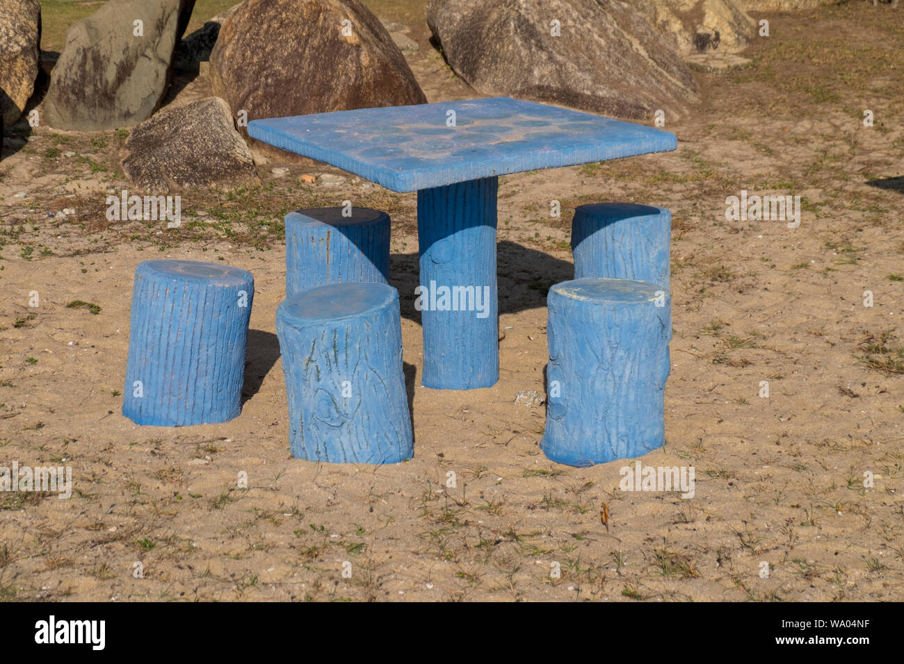 A blue concrete picnic table set that looks like tree stumps on the beach in Kuala Terengganu
