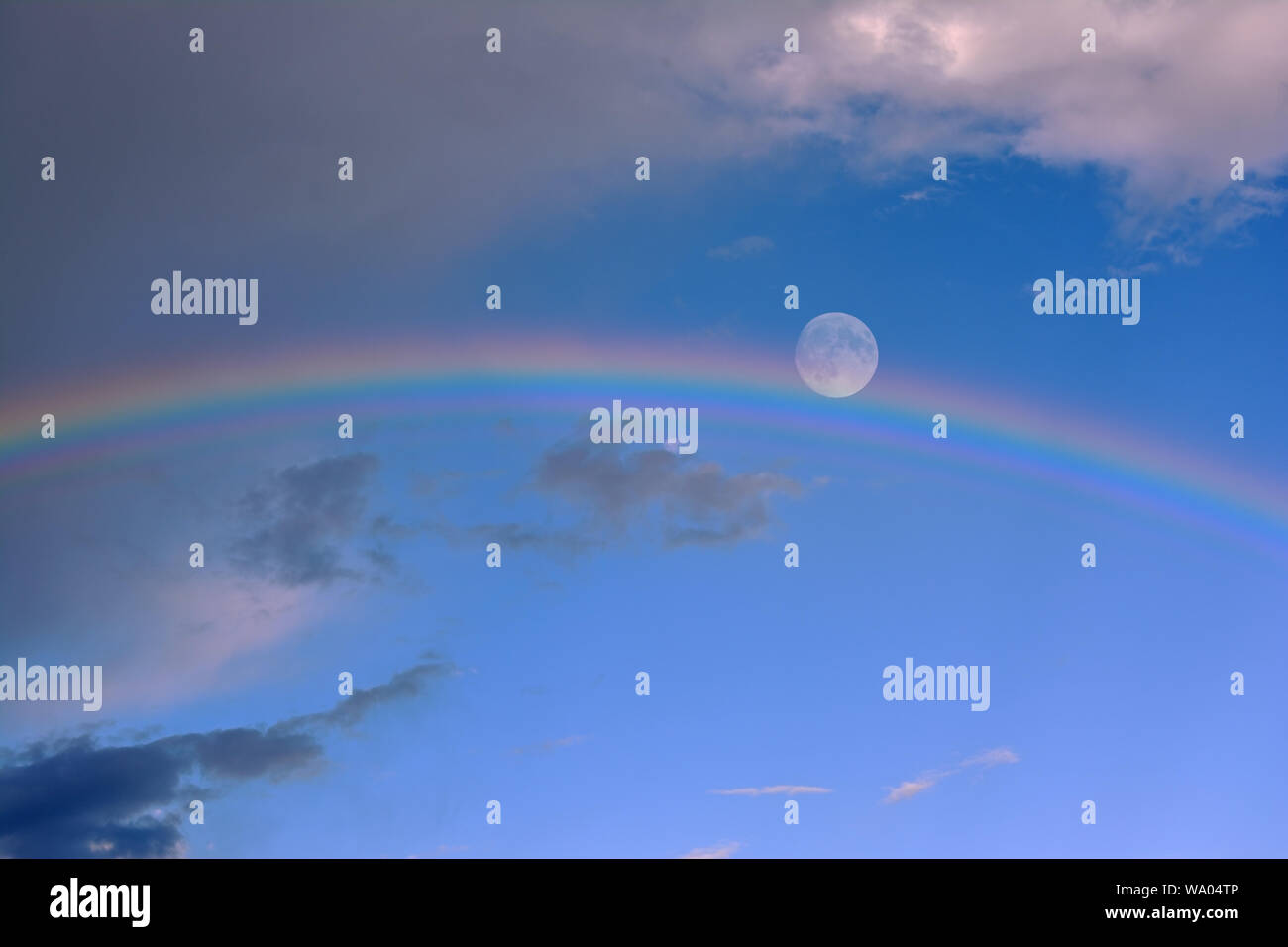 Skyscape with full moon and rainbow Stock Photo