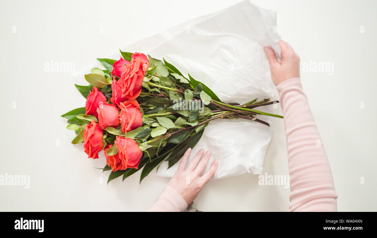Flat lay. Florist wrapping red roses into a beautiful bouquet Stock ...