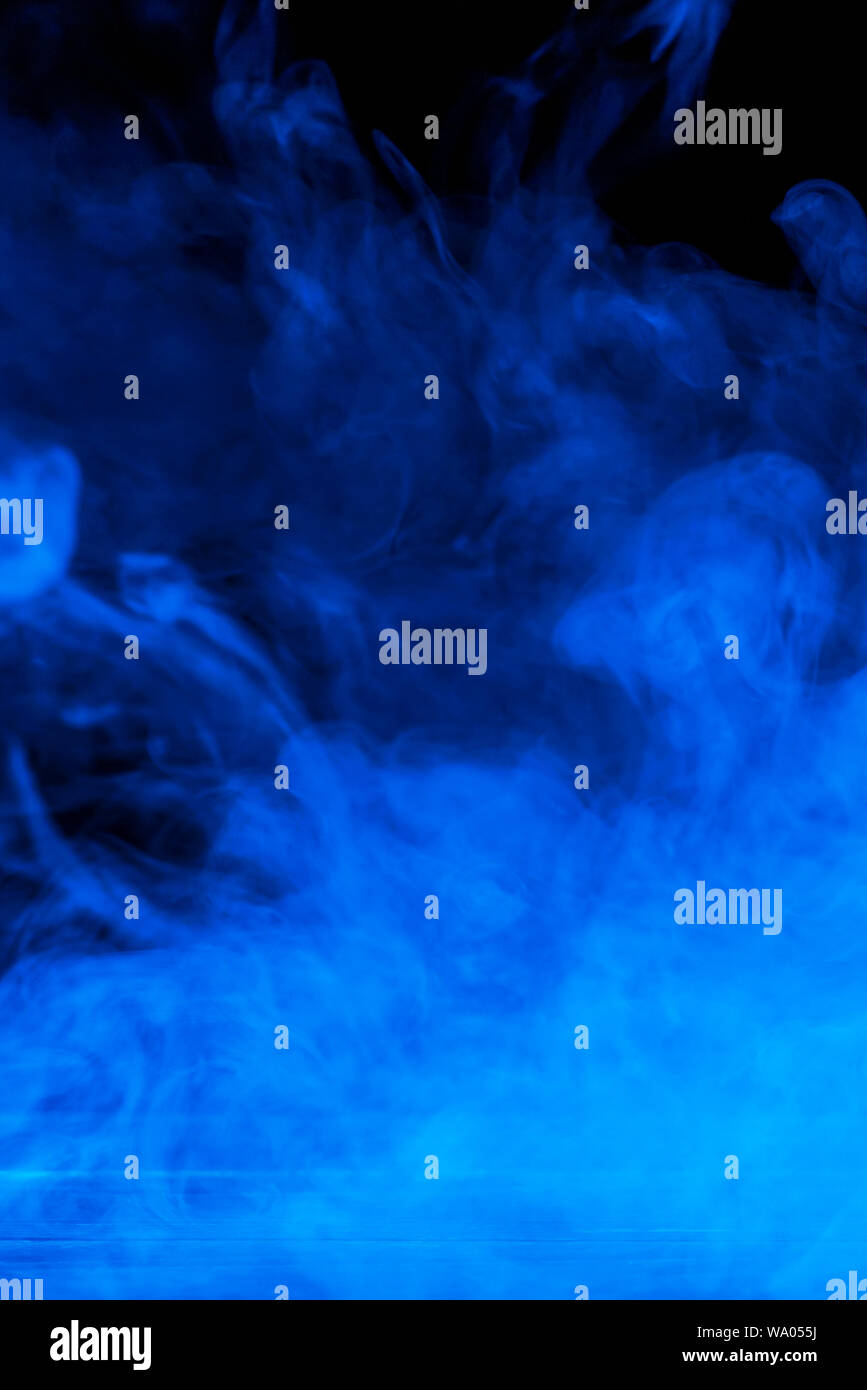 Conceptual image of blue smoke isolated on dark black background and ...