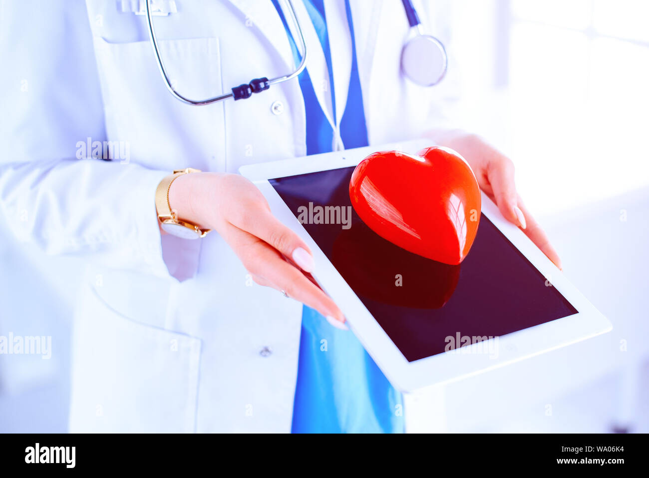 Doctor cardiologist with stethoscope using digital tablet and holding ...