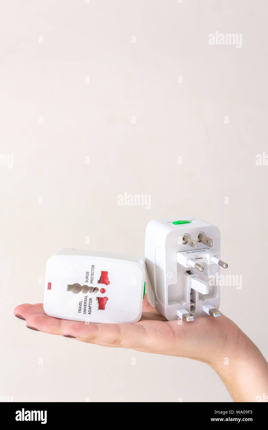 Close up of woman hand holding universal electric socket plug adapters