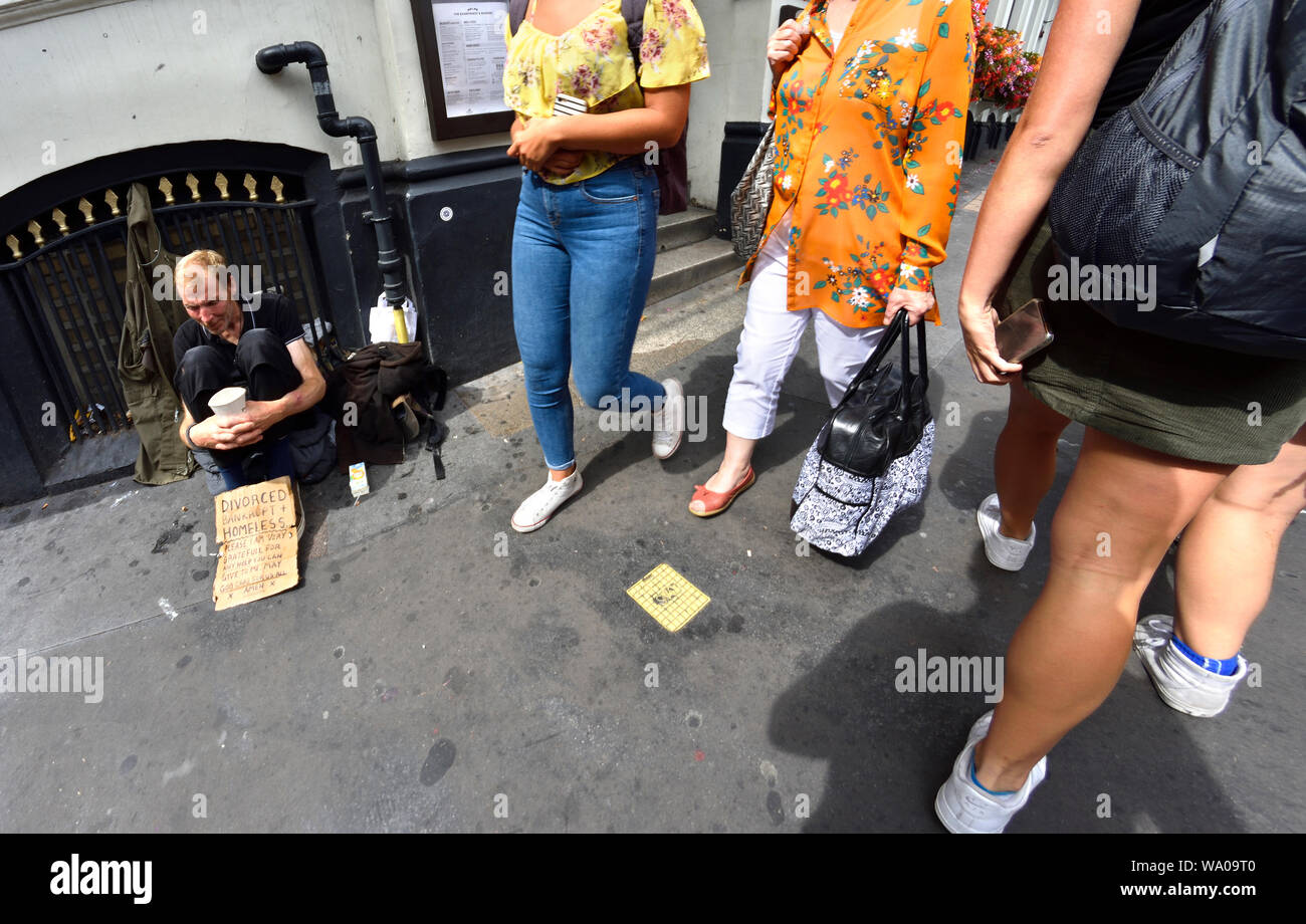 London, England, UK. People walking past a homeless man begging on Southwark Bridge Stock Photo