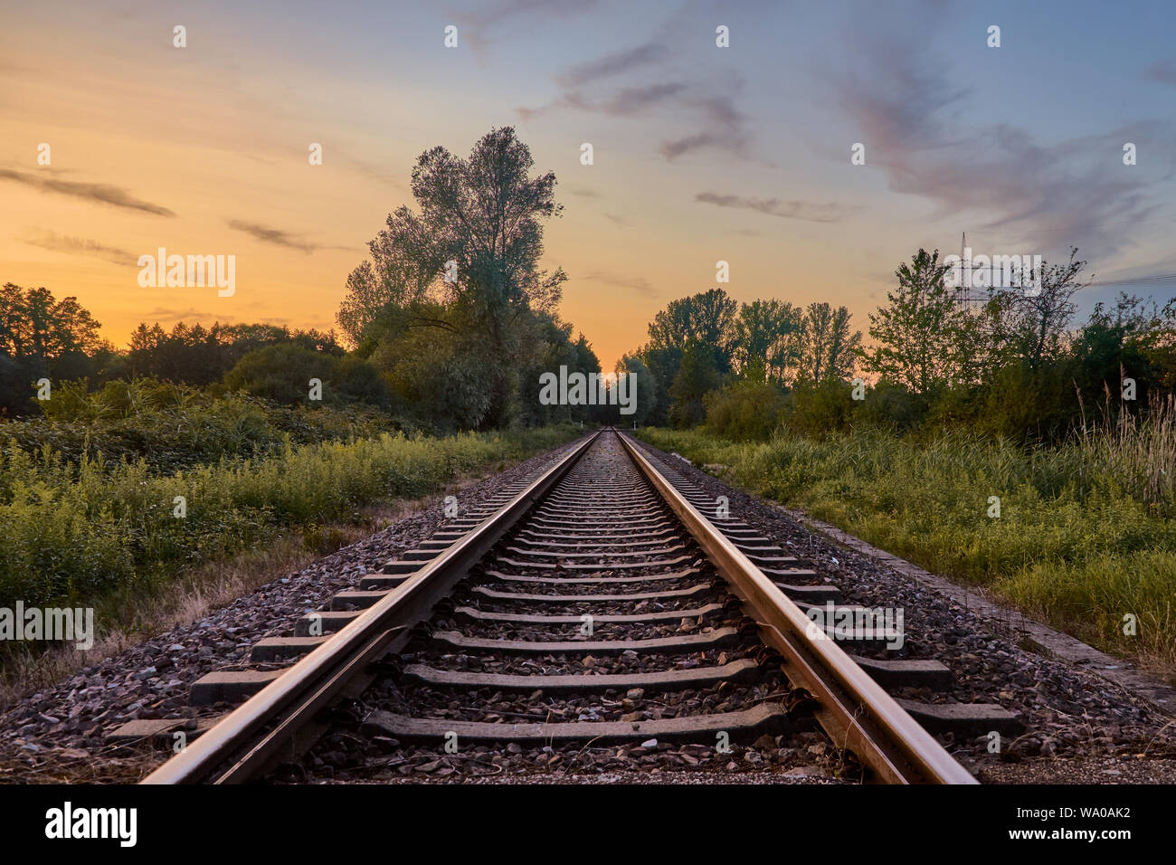 Railroad track in countryside landscape at sunset in Rastatt, Germany Stock Photo