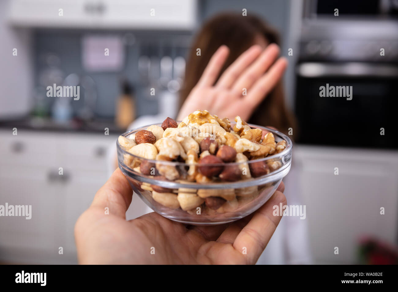 Woman Refusing Bowl Of Nut Food Offered By A Person At Home Stock Photo