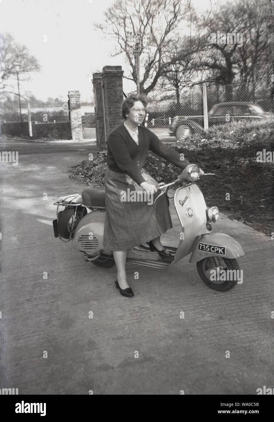 1960s, historical, England and a lady in a skirt sitting outside on a vespa scooter, an Italian made motor scooter manufactured in Tuscany by Piaggio, who were founded in 1946. Stock Photo