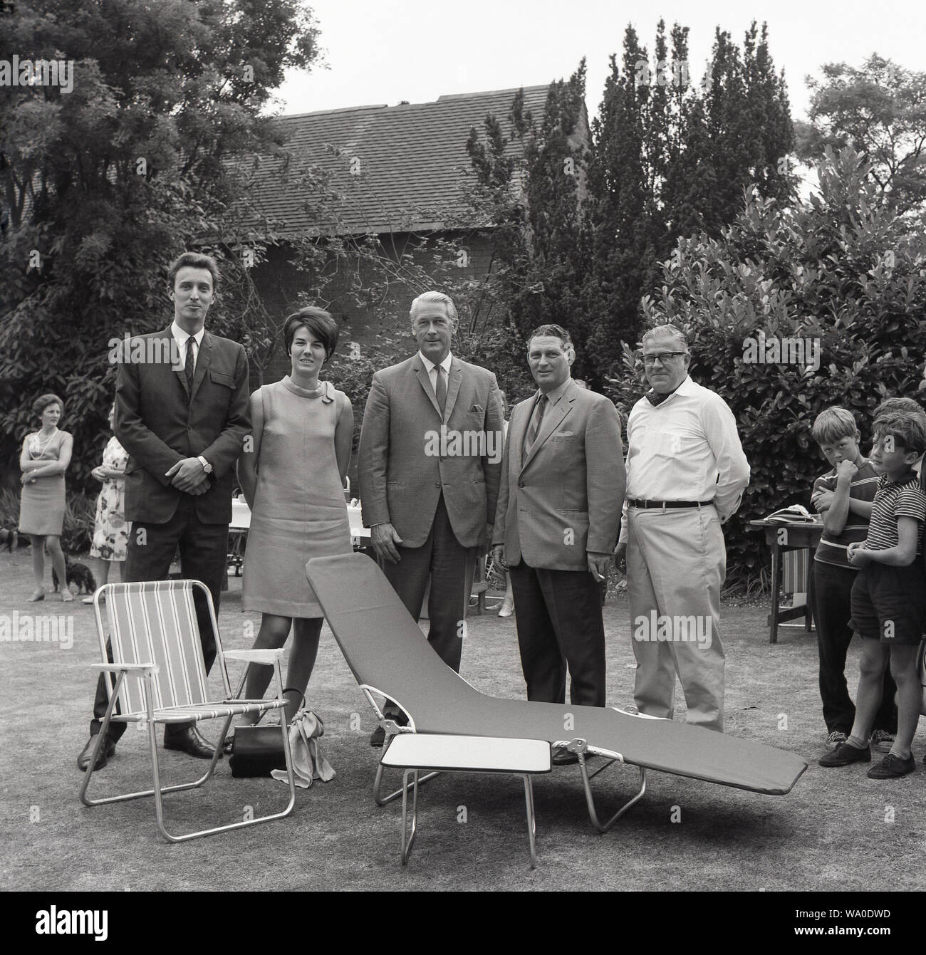 1960s, historical, Prestwood, Bucks, England, people at a fete with the latest designs in garden furniture, a striped metal framed folding garden chair with nylon sling and a metal framed folding sun lounger Stock Photo