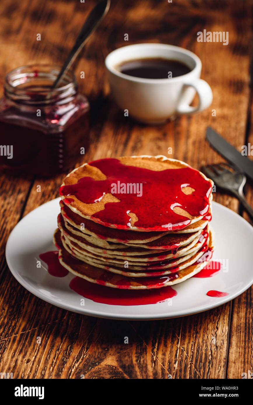 Stack of pancakes with berry fruit marmalade on plate over wooden surface Stock Photo