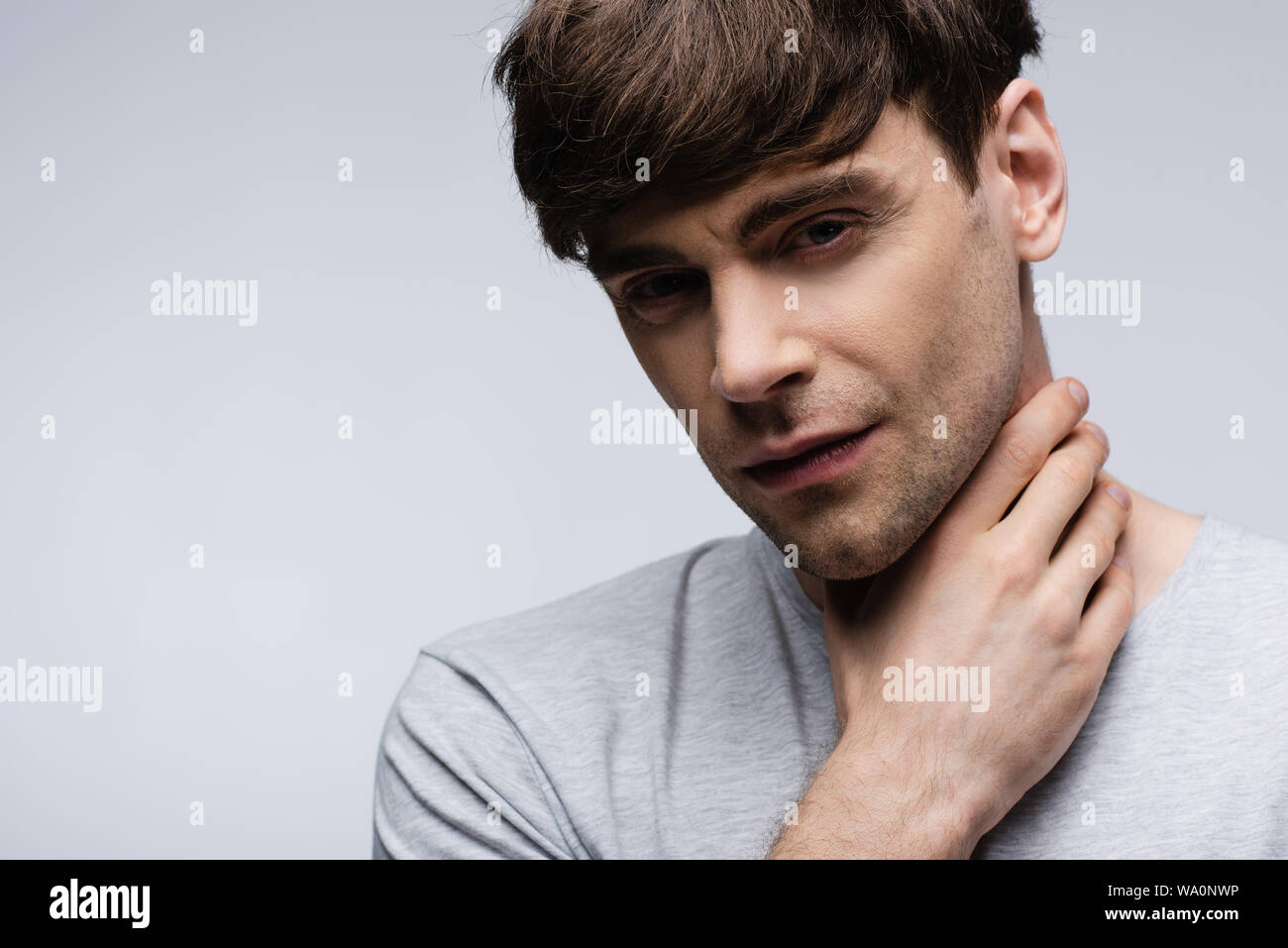 thoughtful man holding hand on neck isolated on grey, human emotion and expression concept Stock Photo