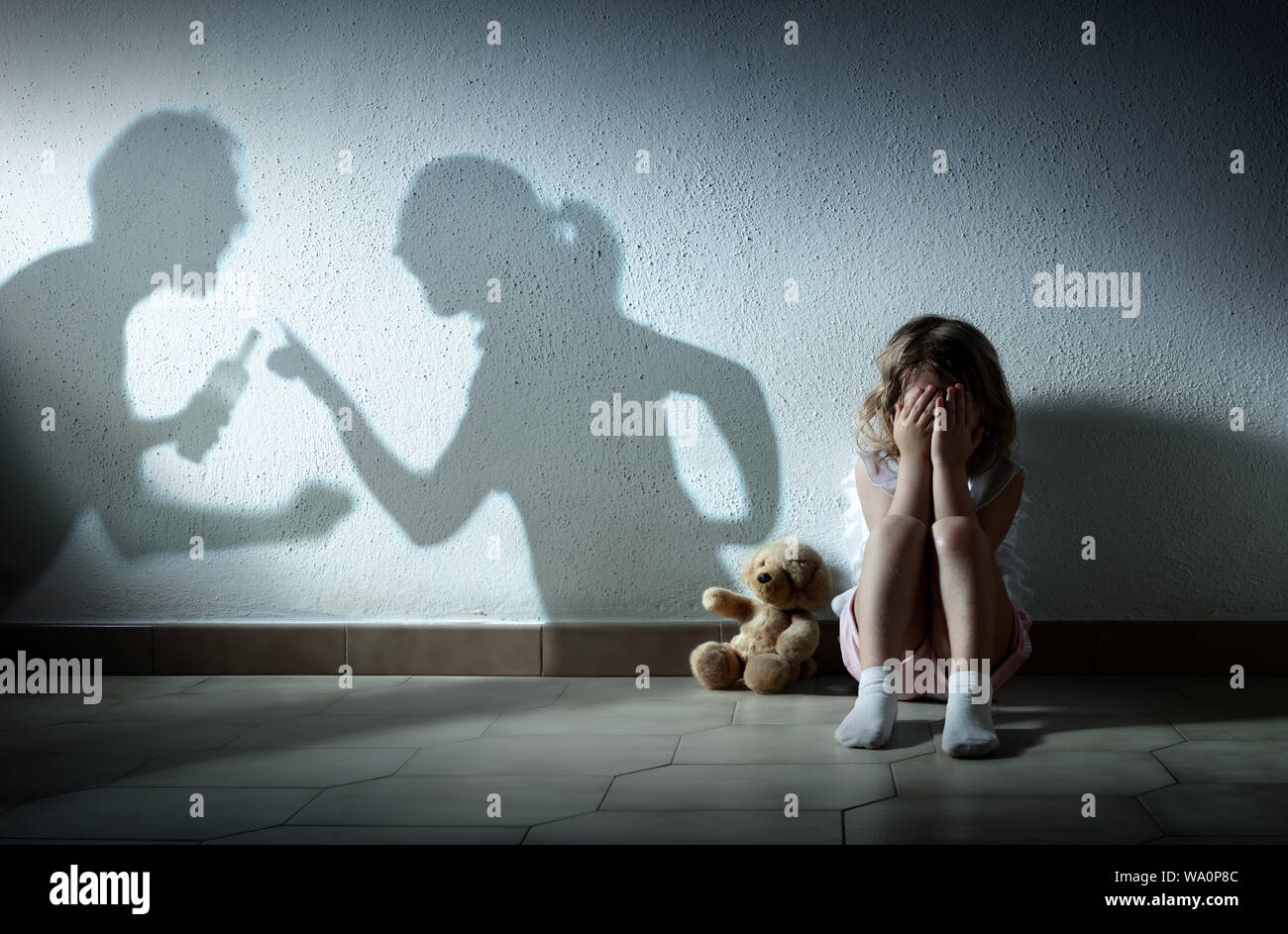 Little Girl Crying With Shadow Of Parents Arguing - Home Violence And Divorce Stock Photo