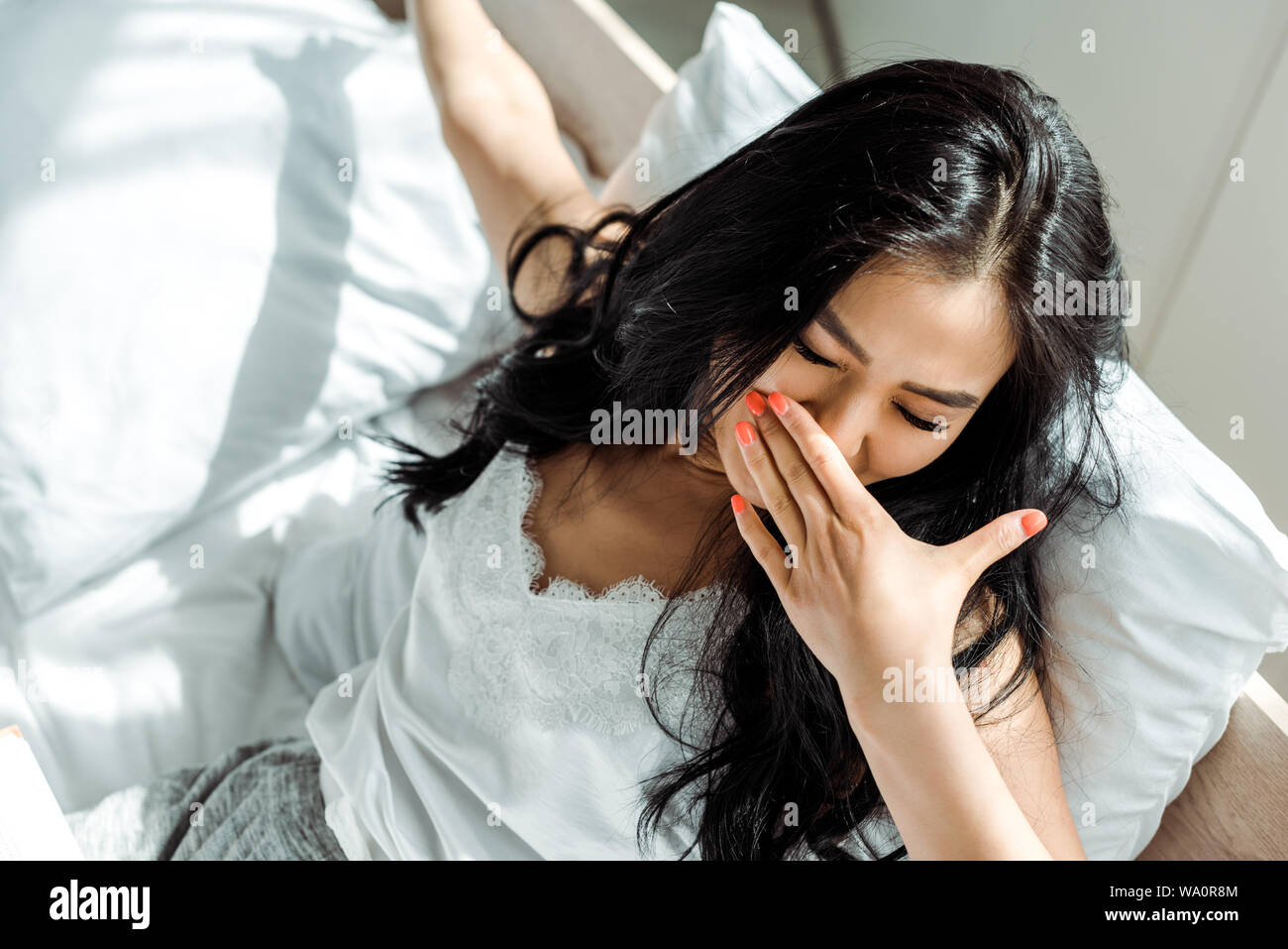 overhead view of asian woman with closed eyes covering face with yawning Stock Photo