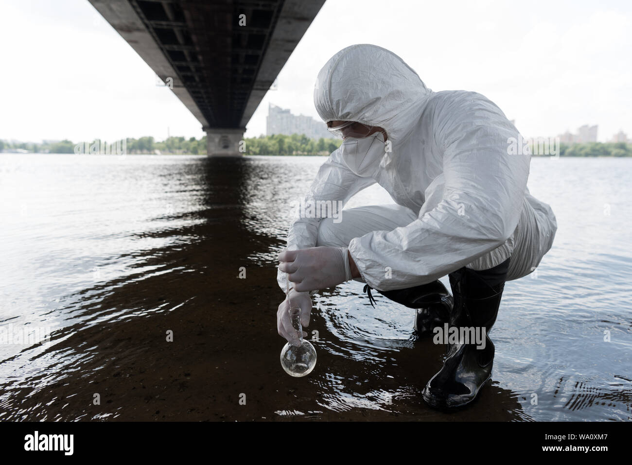 Water Inspector water inspector in protective costume holding flask and taking water ...