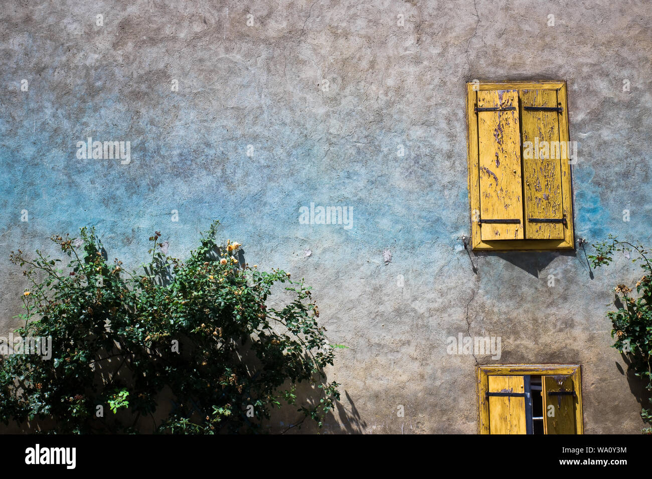 Detail of a stone wall with painted windows in the historic village of Camon. Ariege, France. Stock Photo