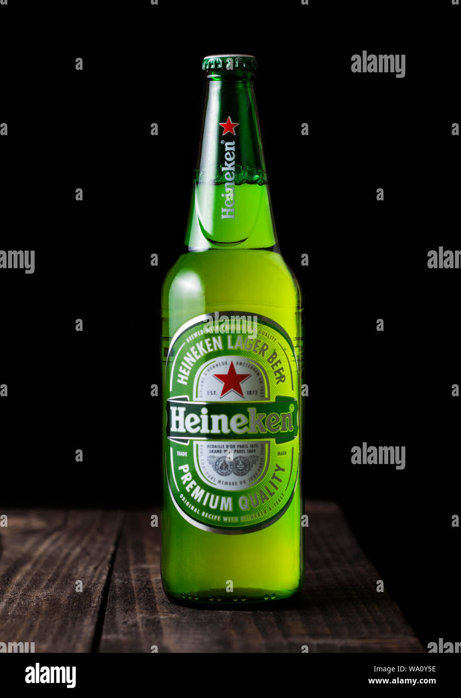 LONDON, UK - APRIL 27, 2018: Bottle of Heineken Lager Beer on dark wooden background. Heineken is the flagship product of Heineken International Stock Photo