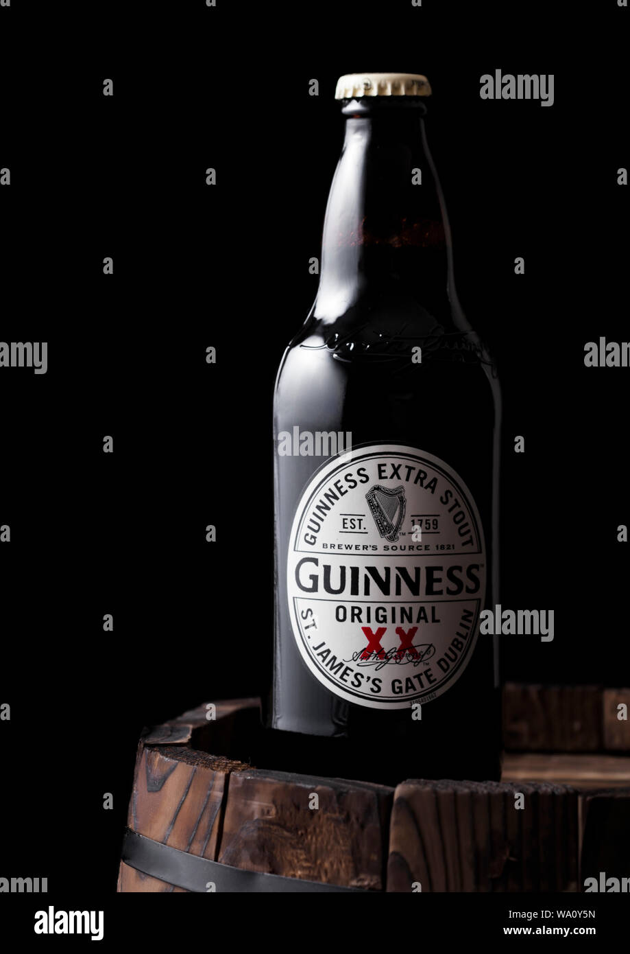 LONDON, UK - APRIL 27, 2018: Bottle of Guinness original stout beer on top of old wooden barrel. Guinness beer has been produced since 1759 in Dublin, Stock Photo