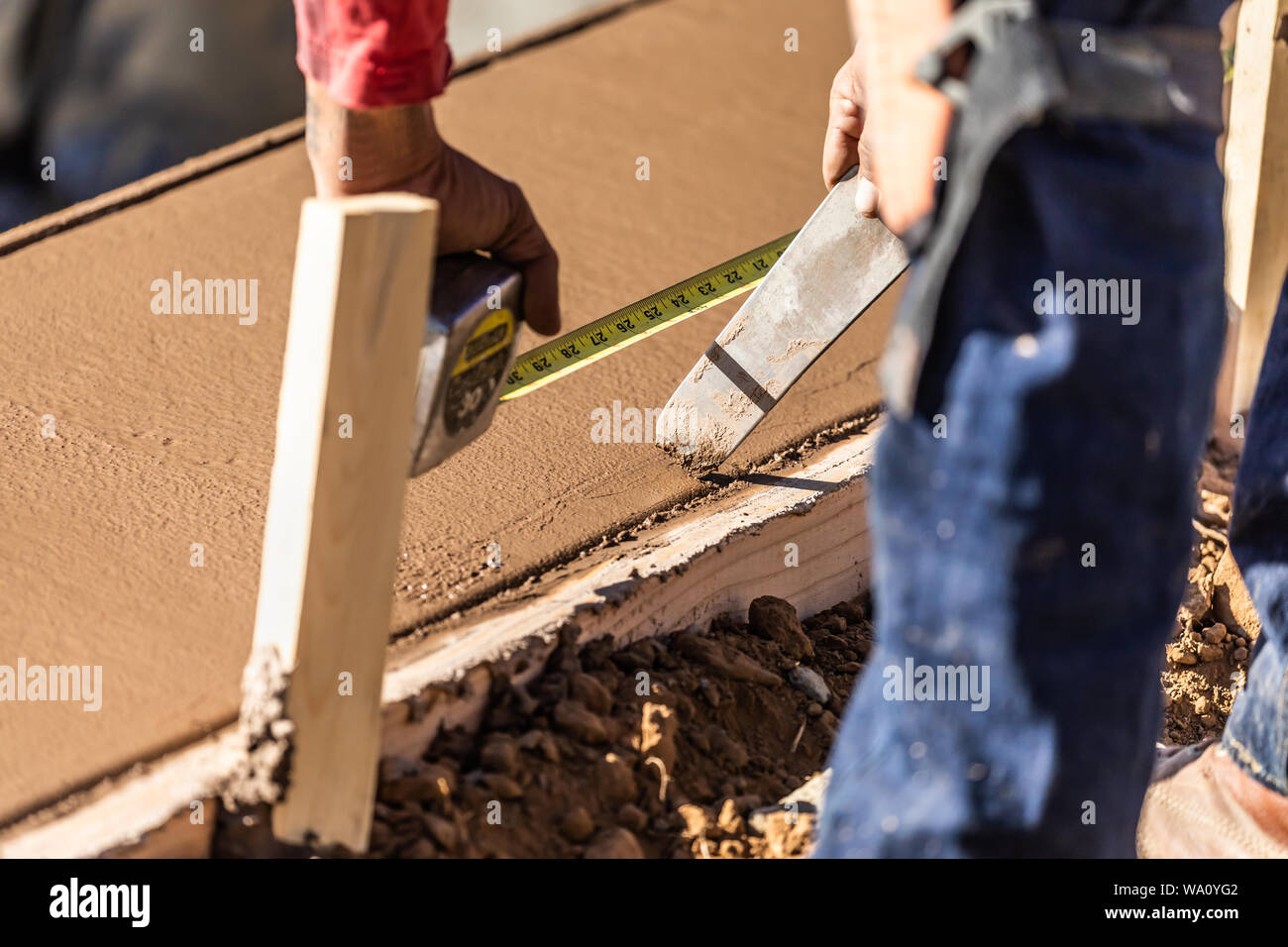 Cement Construction Worker Using Measuring Tape While Forming Pool Coping. Stock Photo