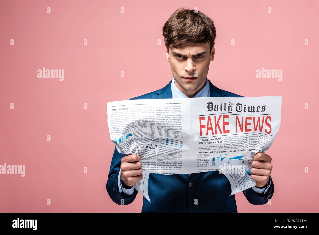 serious businessman holding newspaper with fake news and looking at ...