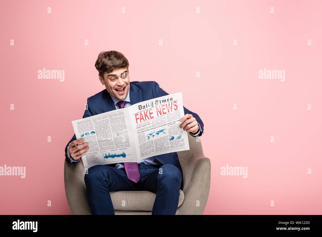 cheerful businessman sitting in armchair and reading newspaper with ...