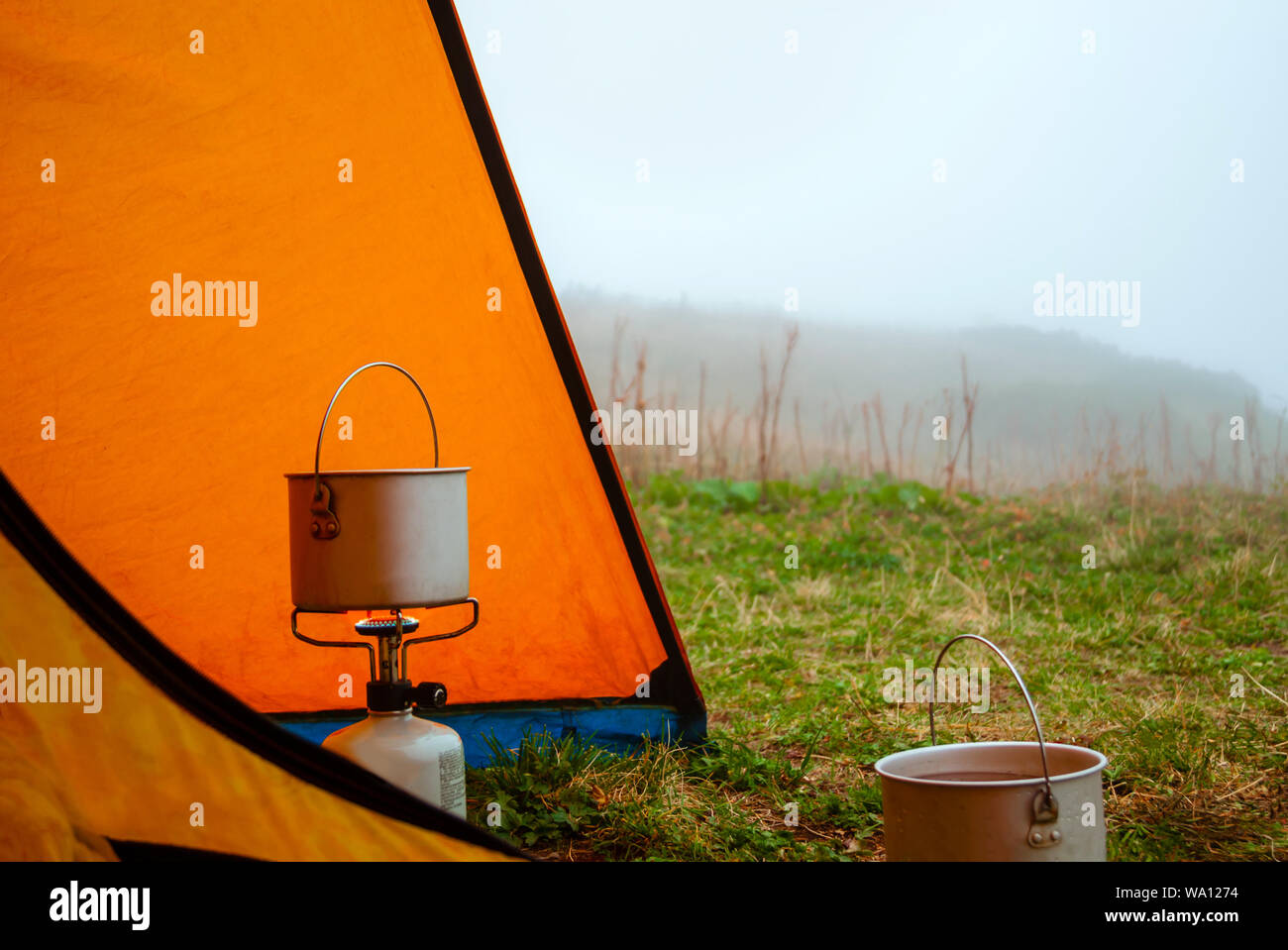 foggy morning in the hike, the view from the tent to the clearing, the hiking pot stands on portable gas burner Stock Photo