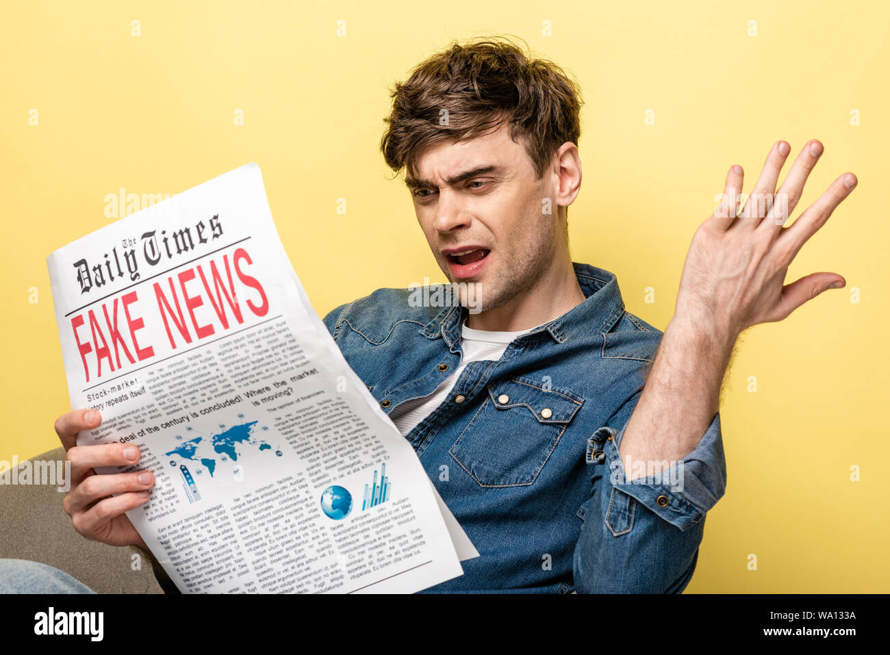 displeased young man sitting in armchair and reading fake news on ...