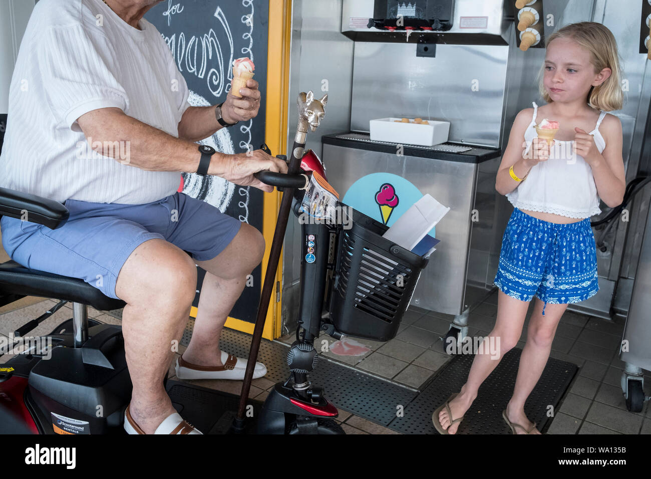 A grand father and his little girl eat an ice cream. Ice creams are free during the whole week. March 21, 2019. Stock Photo