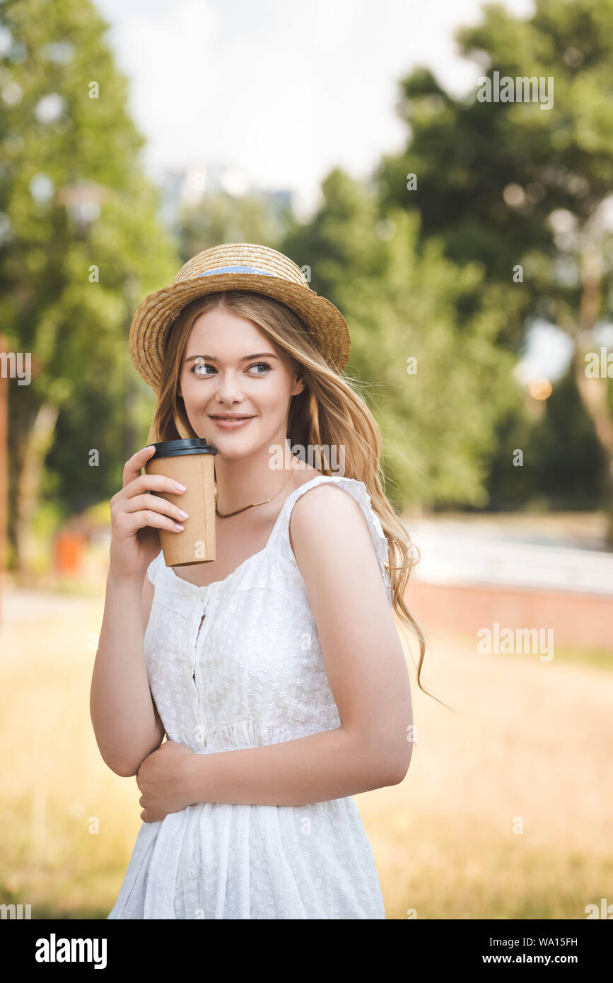beautiful girl in white dress and straw hat holding paper coffee cup ...
