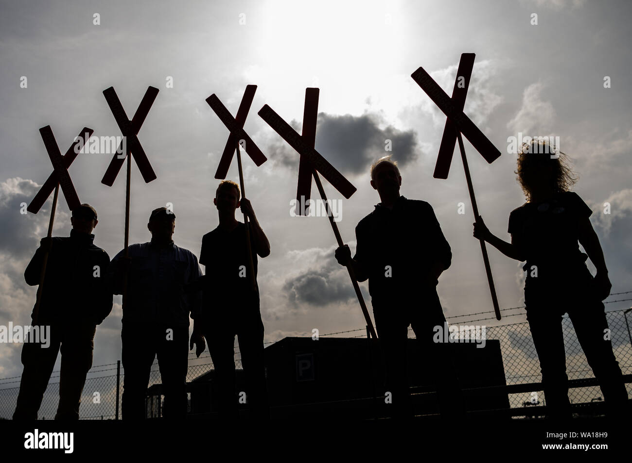 Emlichheim, Germany. 16th Aug, 2019. Members of the citizens' initiative 'NoMoorGas - No natural gas production in our region' stand with crosses in front of the Wintershall Dea oil field. At the oil field in Emlichheim on the Dutch border, reservoir water may have escaped unnoticed for several years since 2014 during a press-in well. Experts speak of up to 220 million litres. Credit: Mohssen Assanimoghaddam/dpa/Alamy Live News Stock Photo