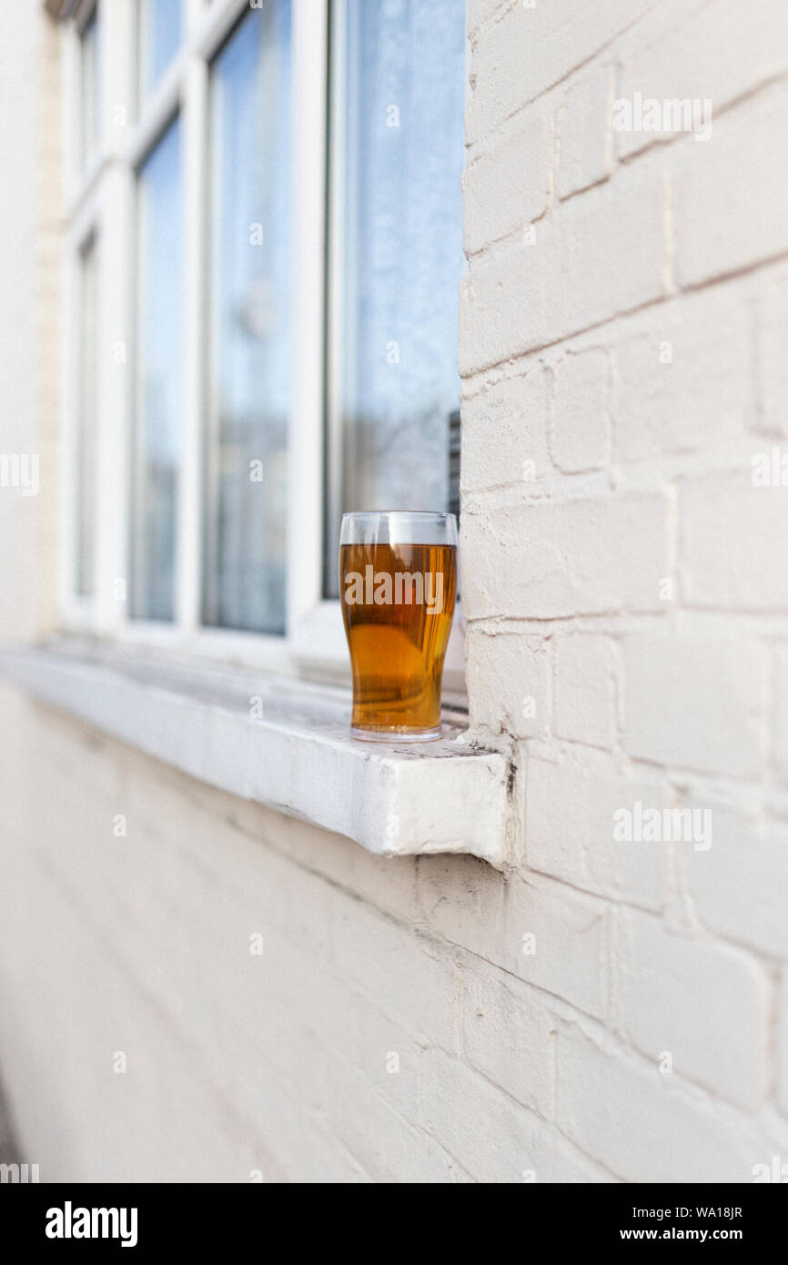 Mostly filled pint glass on window sill outside house in Tooting, London. Stock Photo