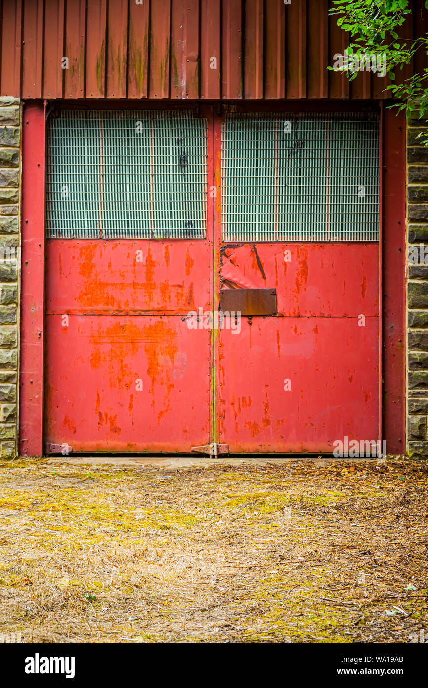 Red doors on an old industrial workshop building or garage, near Consett, County Durham, England, UK Stock Photo
