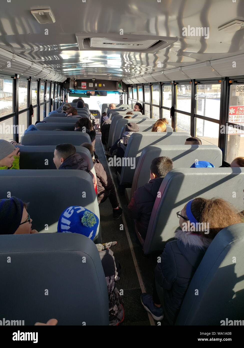 3rd grade students riding the bus back to school after a class outing. Stock Photo
