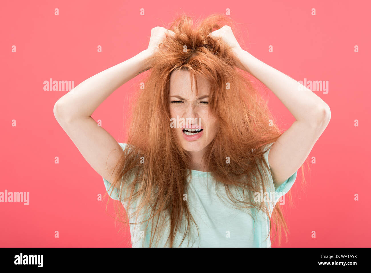 Angry Redhead Woman Touching Tangled Hair And Screaming Isolated