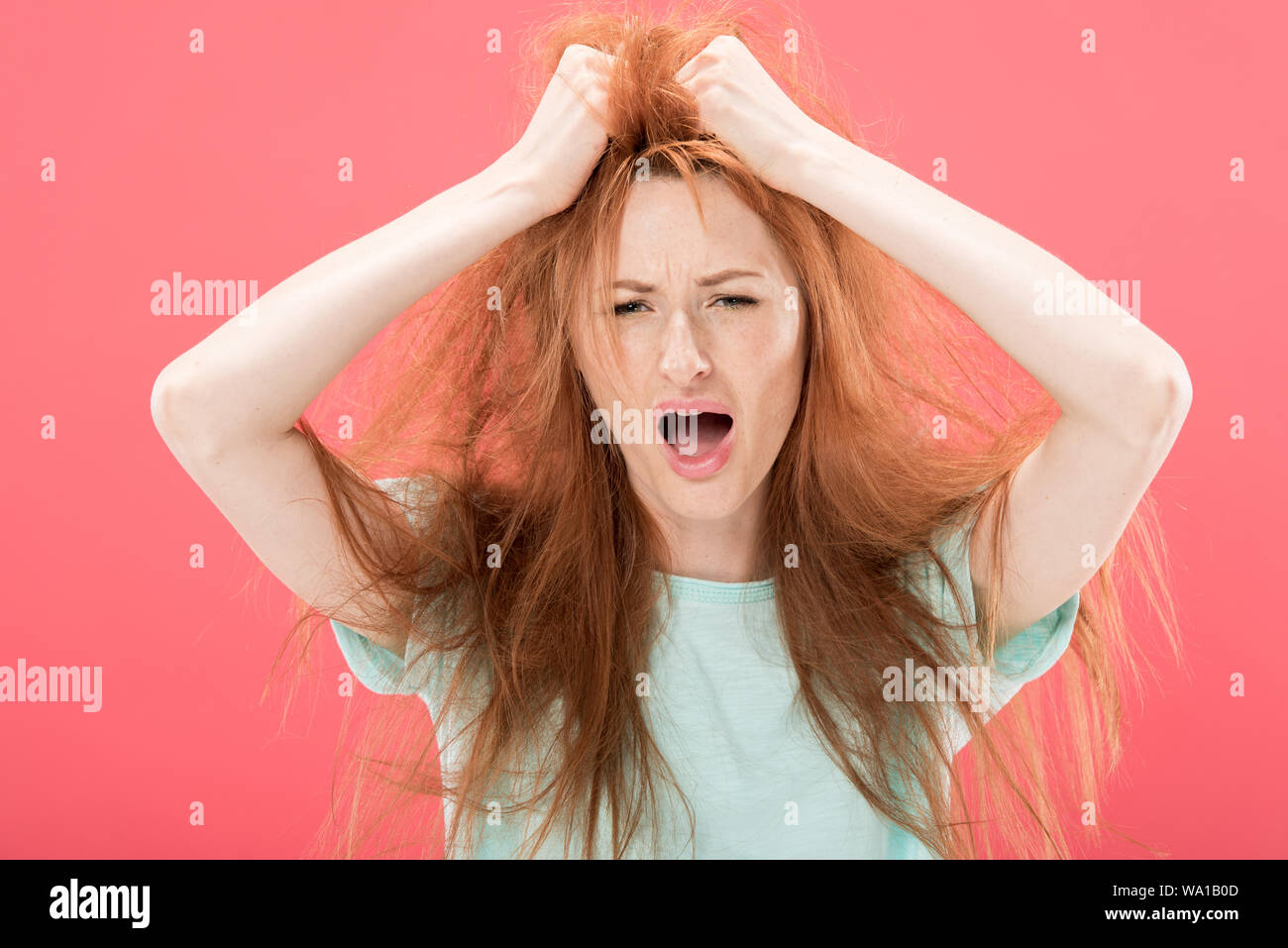 Angry Redhead Woman Touching Tangled Hair And Screaming Isolated