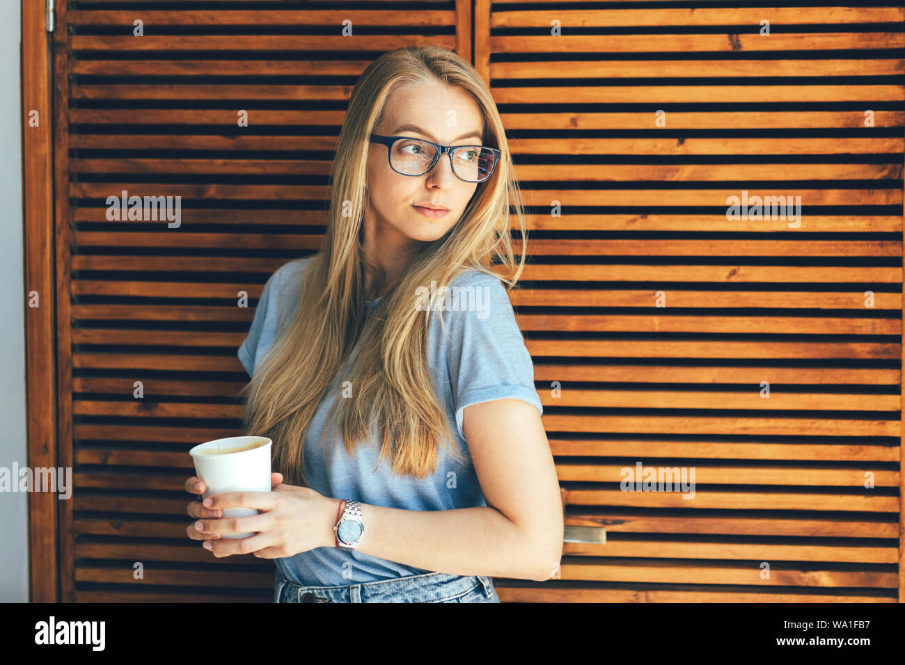 blonde in glasses with a paper cup of coffee inside Stock Photo