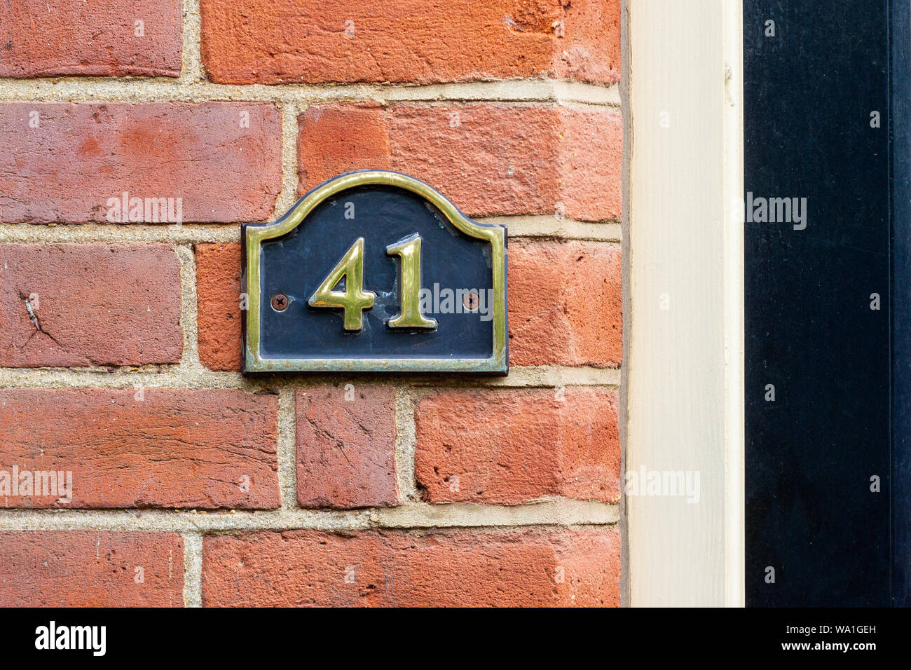House number 41 on a black metal sign on a red brick wall Stock Photo